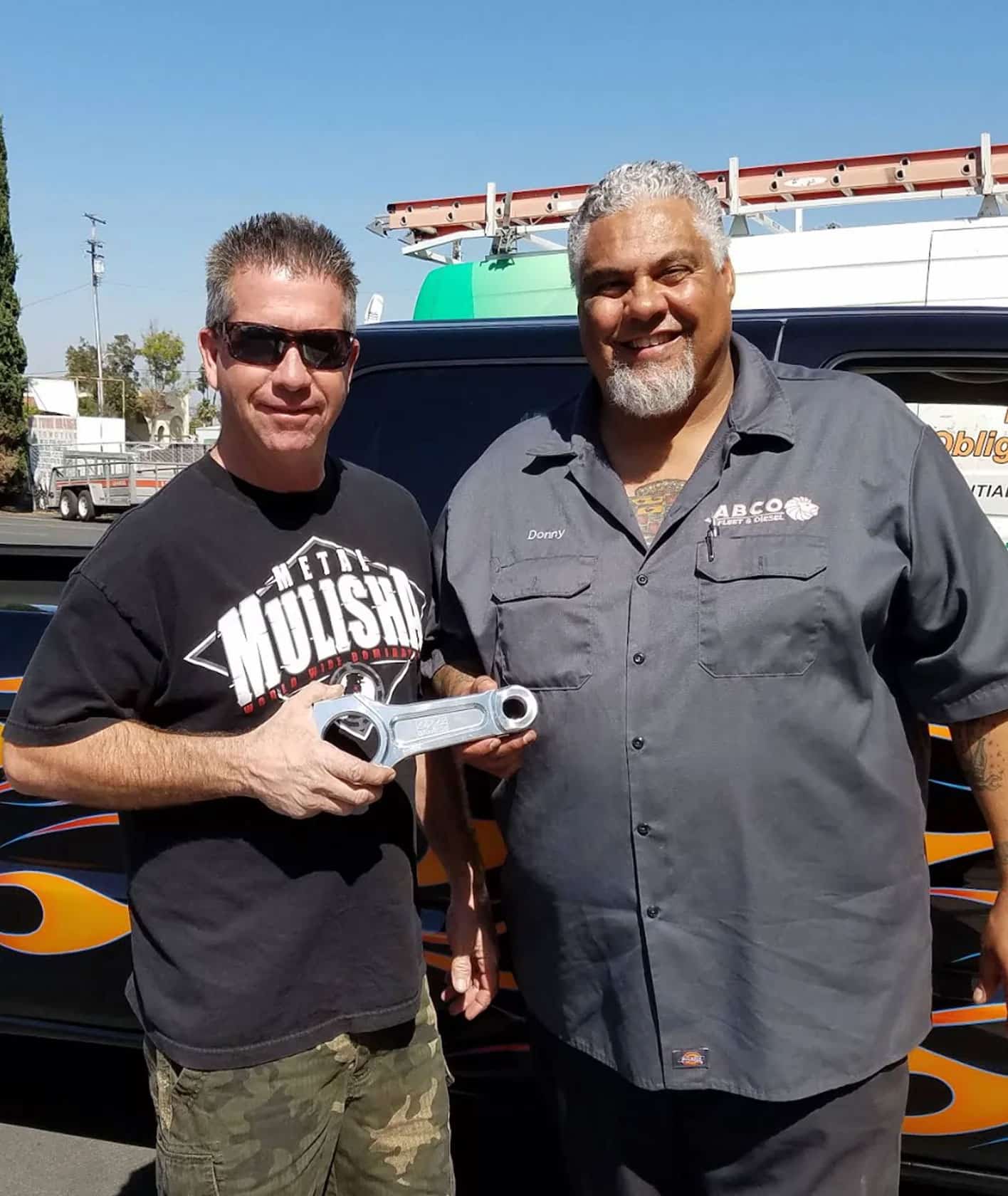 two men standing next to a car